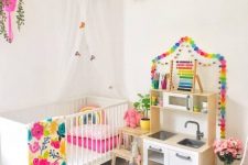 a rainbow splashed kid’s room with colorful garlands, a bold rug, colorful bedding and a hot pink planter