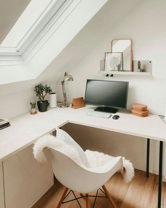 a small Scandinavian corner working space with an L-shaped desk, a white chair, a shelf with decor and some plants