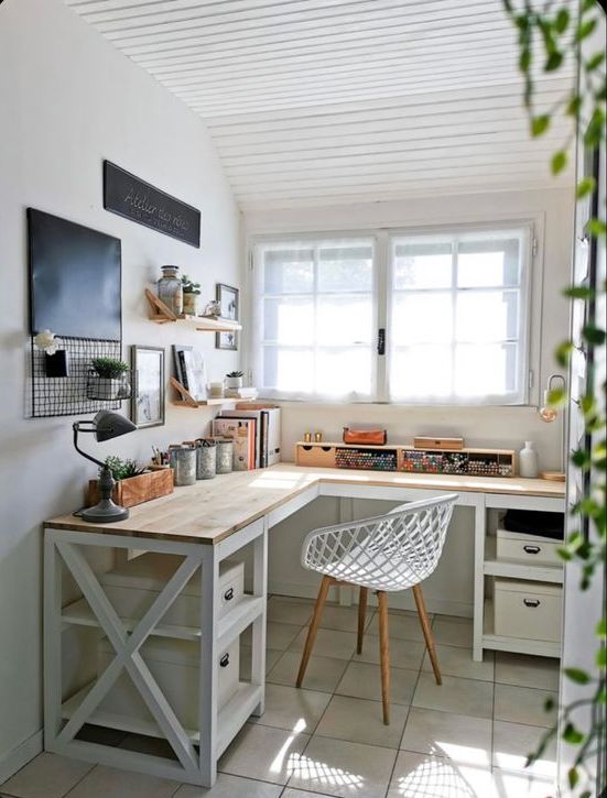 a small art studio with a corner desk, storage boxes, a white chair, open shelves and decor is lovely