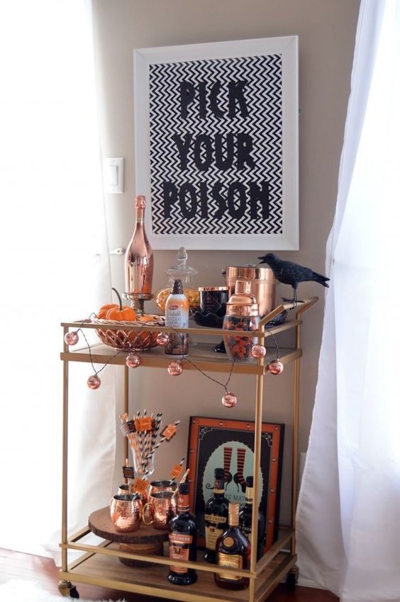 a stylish Halloween bar cart with a pumpkin garland, a crow, copper barware, signs and artworks