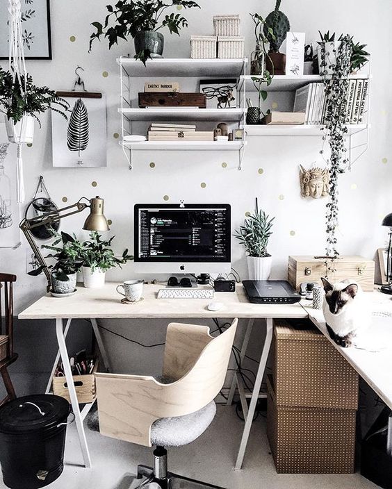 a stylish Scandinavian home office with a trestle corner desk, boxes, greenery, a polka dot wall and a plywood chair