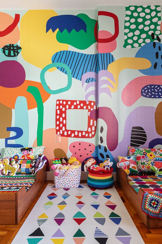 a super colorful shared kid's bedroom with a bold abstract wall, colorful linens and baskets, bold toys