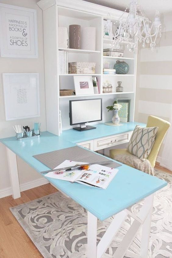 a vintage farmhouse home office with a blue corner desk and a storage unit on one side, a yellow chair and a glam crystal chandelier