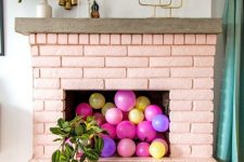 02 a blush brick fireplace filled with colorful balloons and with potted plants all around is a very cheerful and fun idea