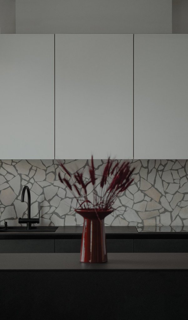 The kitchen is minimal, with white and grey cabinets, a black kitchen island and a catchy backsplash The kitchen is minimal, with white and grey cabinets, a black kitchen island and a catchy backsplash