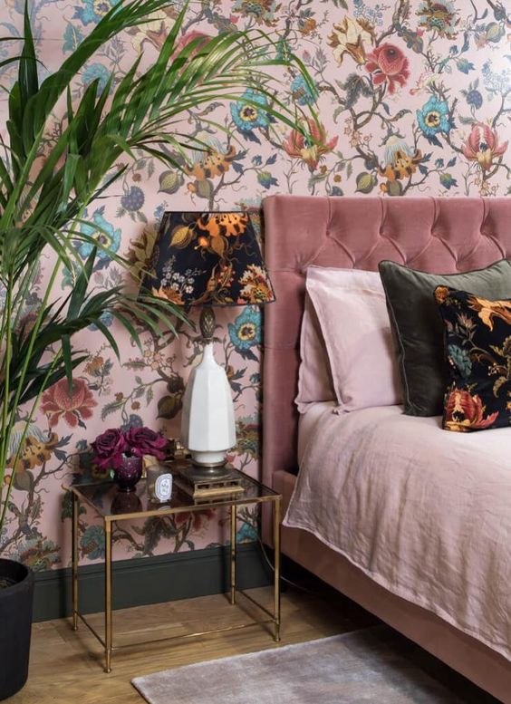 a refined bedroom with a pink floral accent wall and a dark floral table lamp that echoes with it