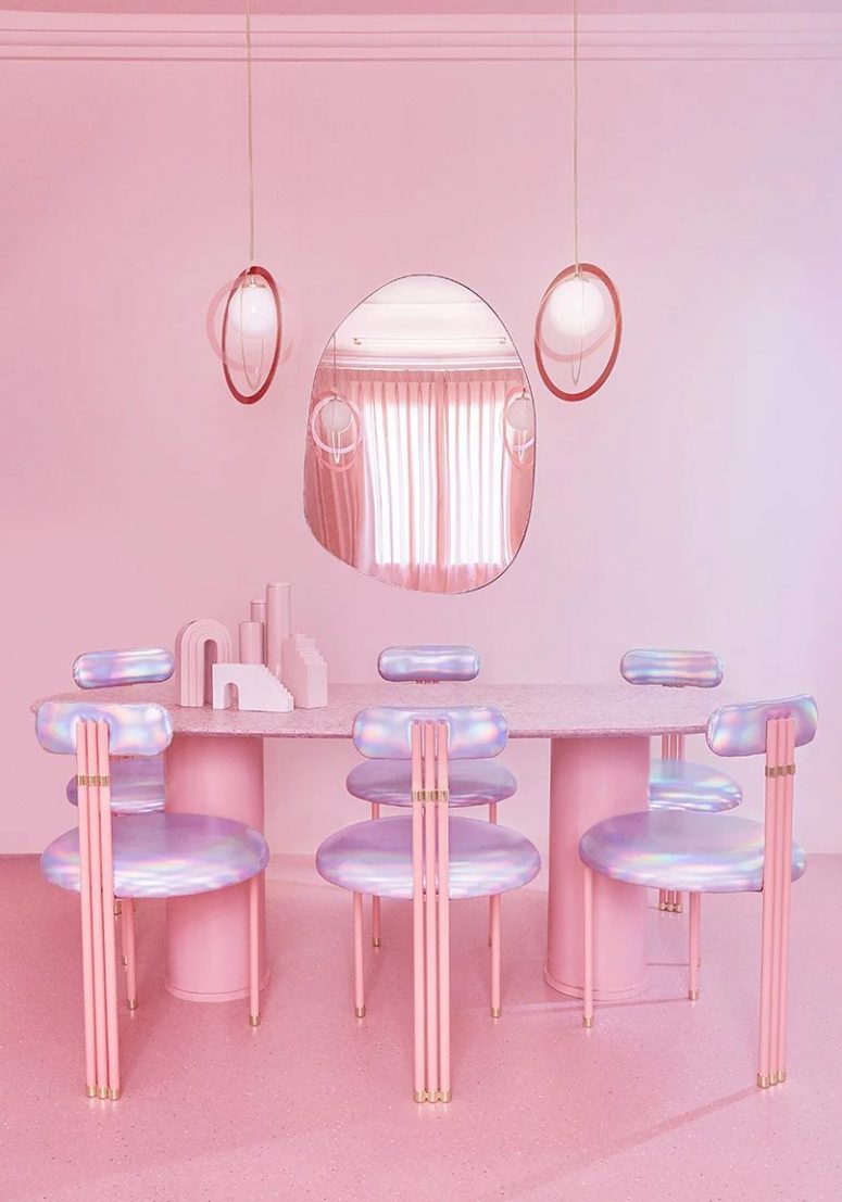 The dining room is done with a pink oval table, iridescent chairs and pendant lamps plus an oddly shaped mirror The dining room is done with a pink oval table, iridescent chairs and pendant lamps plus an oddly shaped mirror