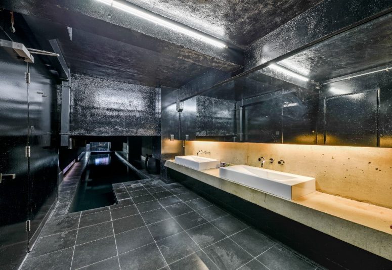 The bathroom is all black, with a stone vanity and tiles and other surfaces in black