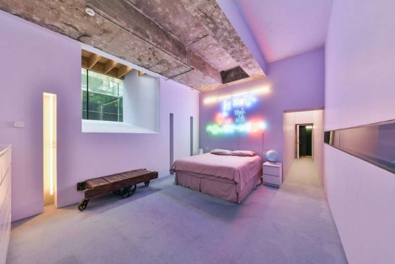 The aster bedroom is pink and lavender, with a neon sign and a rough concrete ceiling