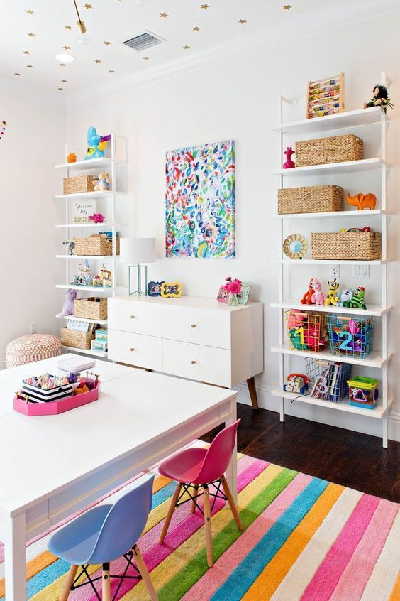 a colorful and bold playroom with open storage units, a bold artwork and bright rug, furniture and accessories