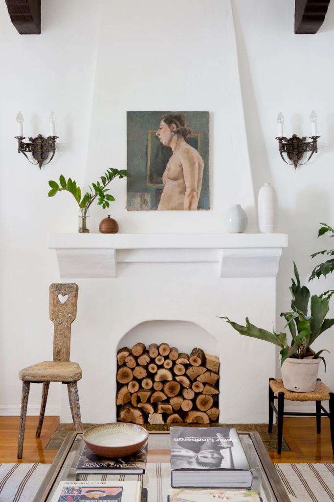 a stylish white non-working fireplace with very natural firewood inside is a chic idea with a rustic feel
