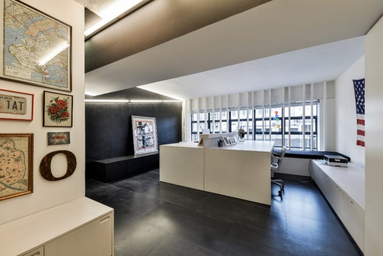 The home office is black and white, with two white desks, built-in lights and built-in storage units