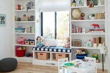 09 a vivacious playroom with open storage spaces, a windowsill bench, white furniture and colorful toys and books
