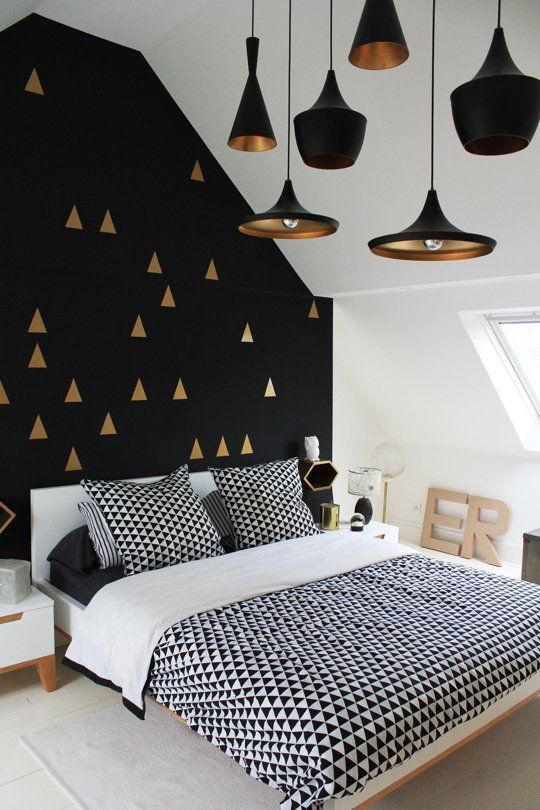 a gorgeous black and gold geometric pattern accent wall plus black and brass pendant lamps that echo with it