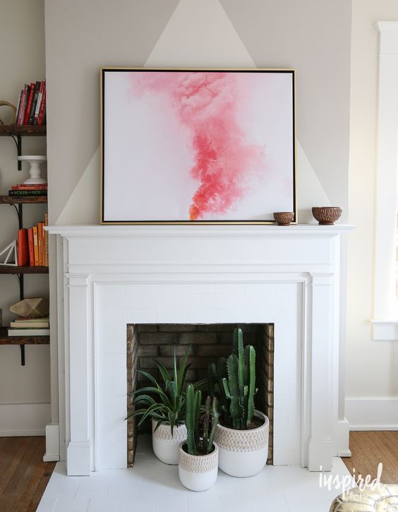 a non-working brick fireplace with a white surround and mantel plus cacti and succulents in pots inside it is wow