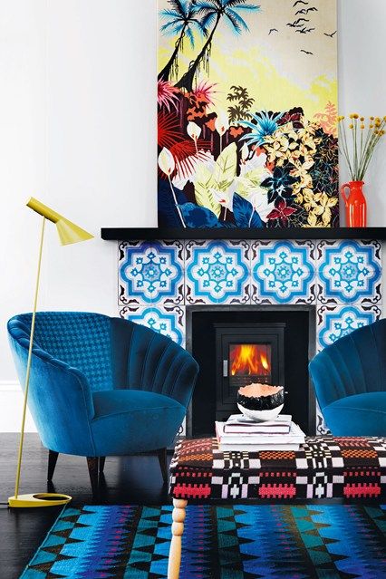 electric blue chairs, a bright blue printed rug, a bold blue tile fireplace and a colorful artwork create color galore that will raise your mood