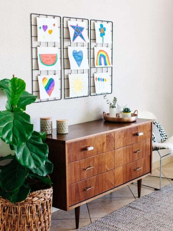 several grids attached to the wall with bold artworks of your kids is a cool idea that will allow to add or remove some of art pieces