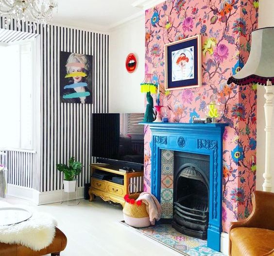 a blue fireplace with colorful tiles and pink floral wallpaper around that accent the hearth even more