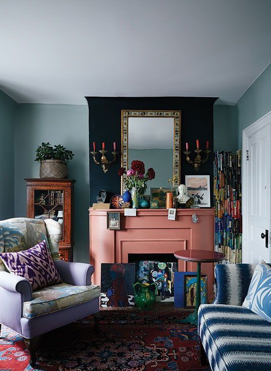a bright whimsical living room with a salmon pink fireplace and colorful artworks looks unusual and very eye-catchy