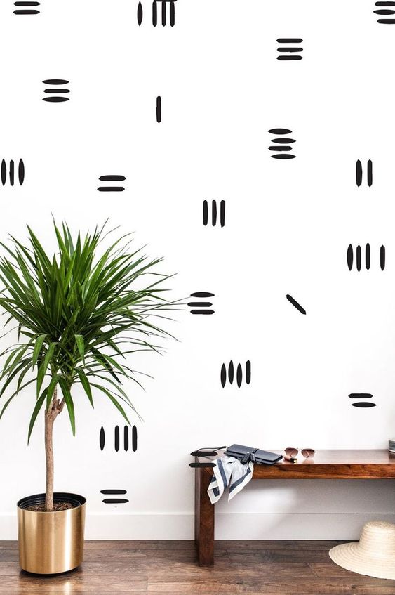 a boho entryway with a monochromatic accent wall with stripes is a bright and fun idea for a modern space