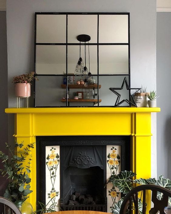 a vintage fireplace with floral tiles on each side and a sunny yellow mantel looks very refined and vintage-inspired