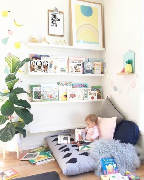 a cozy reading nook with a soft seat with pillows and ledges with books, some art and some plants