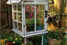 24 a large greenhouse with lots of planters built completely of old window frames and with bright blooms inside is very nice for outdoors