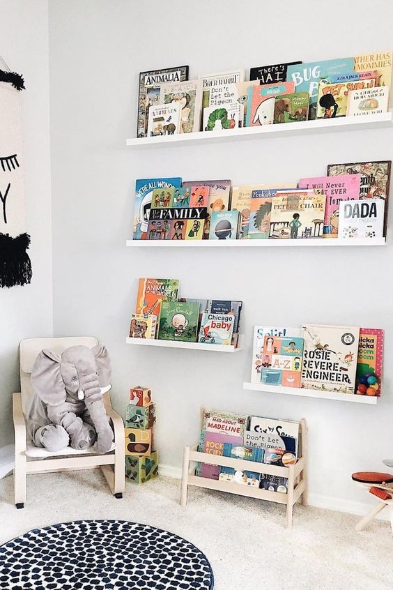 a contemporary reading nook with white and light stained furniture, bold books and toys