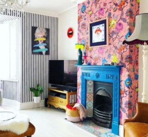 a blue fireplace mantel, colorful tiles and pink floral wallpaper around that accent the hearth even more