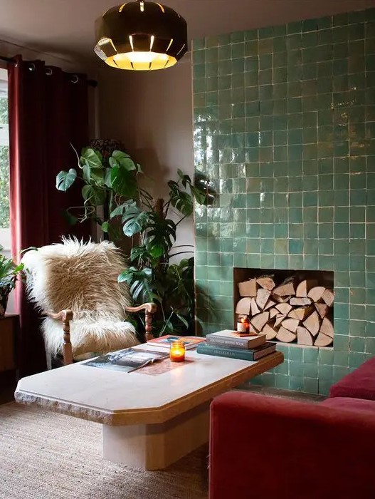 a bold living room with a non-working fireplace surrounded with green Zellige tiles, with firewood inside