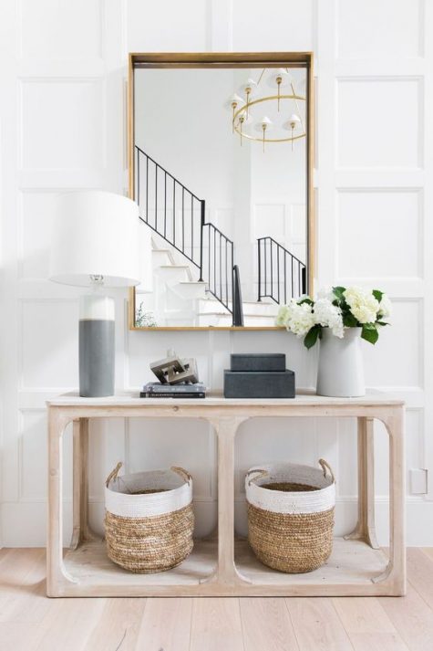 a chic modern entry with a large mirror, a pretty wooden console with baskets and a color block lamp is simple and stylish