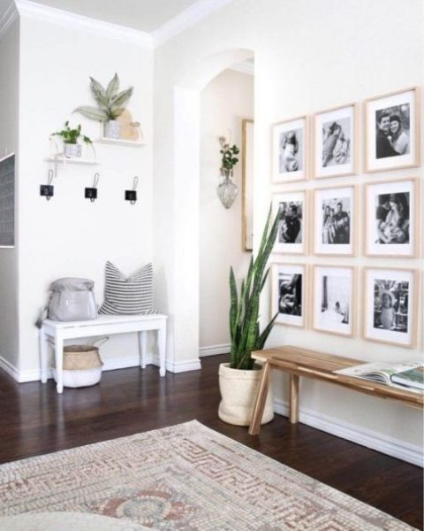 a chic modern entryway with a couple of benches, a gallery wall, some plants and clothes racks