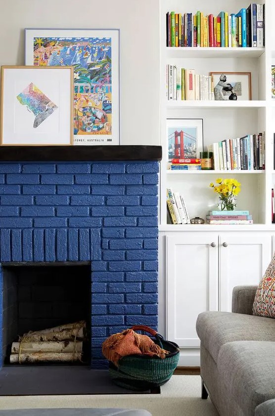 - تصآميم مدفأة ملونة انيقة .. ! A-chic-modern-living-room-with-a-grey-sofa-a-navy-brick-fireplace-built-in-shelves-and-a-cabinet-and-some-bold-artwork