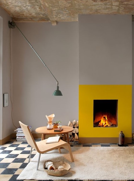 - تصآميم مدفأة ملونة انيقة .. ! A-contemporary-space-with-dove-grey-walls-and-a-checked-floor-a-fireplace-accented-with-a-bit-of-yellow-paint-firewood-a-cool-wall-lamp-and-some-books