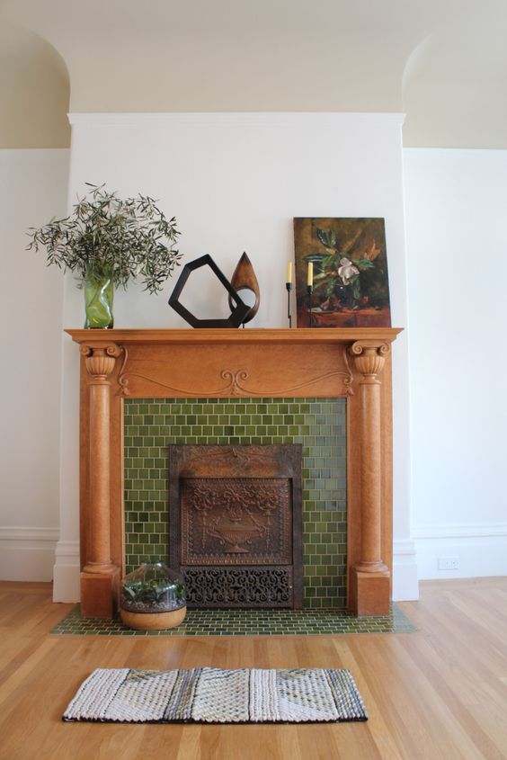 a fireplace clad with green tiles, with a stained mantel and some chic vintage decor is a lovely idea for a living room