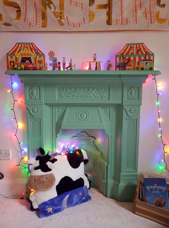 a light yellow mantel and a non-workign fireplace, toy decor on the mantel and some lights for a kids' room