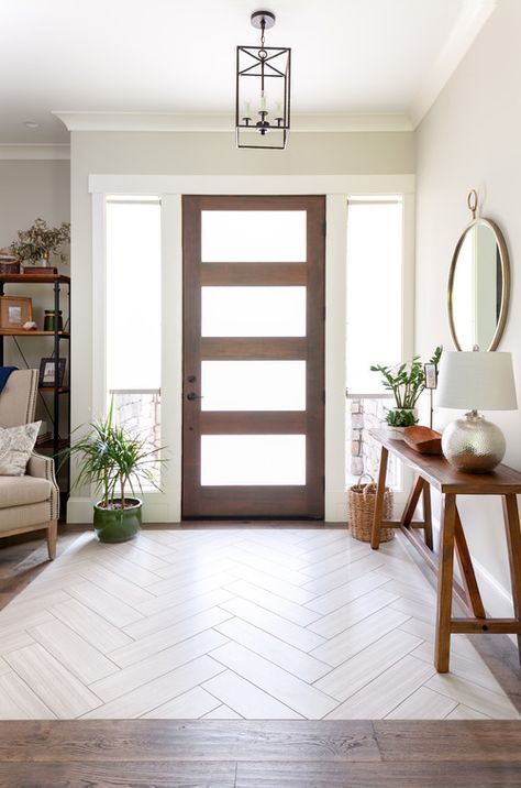 a modern and simple entryway with a bench-like console, potted plants, a round mirror and a basket