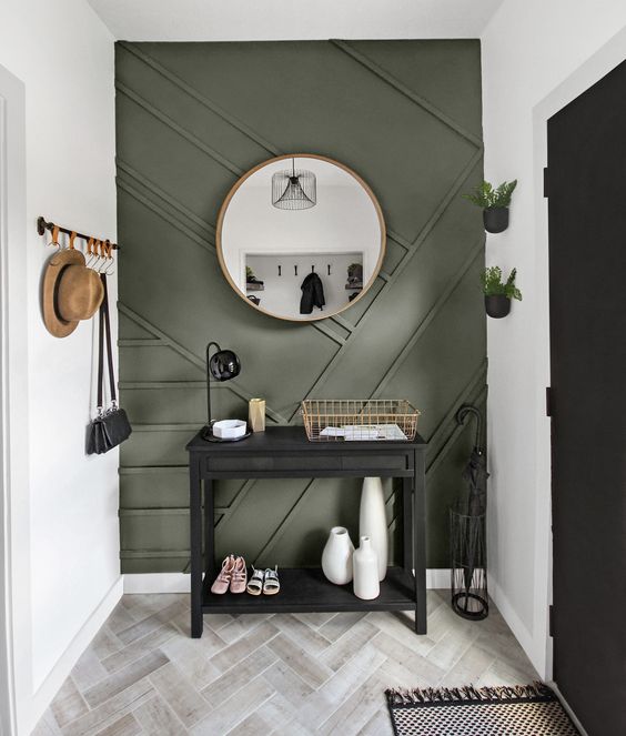 a modern entryway with a green paneled wall, a black console, some railings and planters on the wall