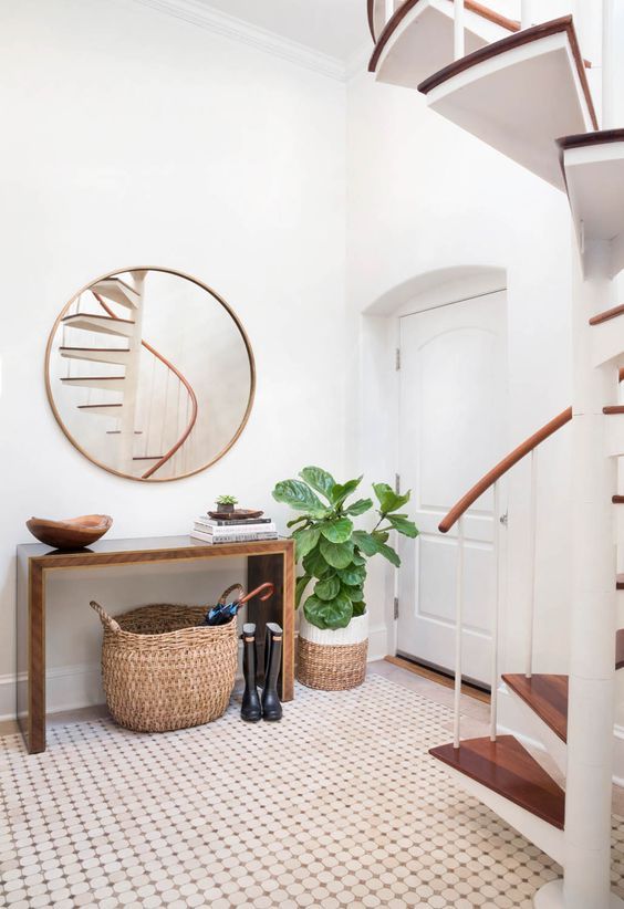 a modern entryway with a wooden sleek console, a round mirror, some baskets and a statement plant