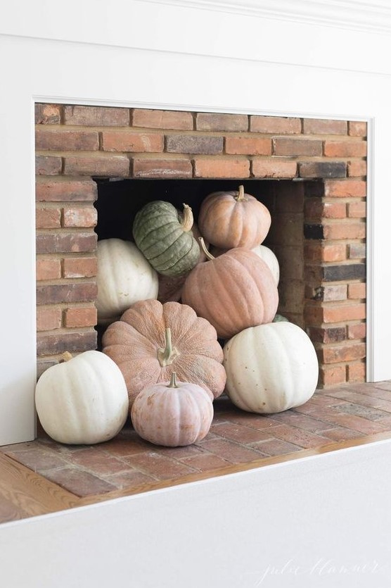 a modern fireplace with neutral and pastel pumpkins is a cool idea for a modern fall-embracing space and is an easy to realize decor idea