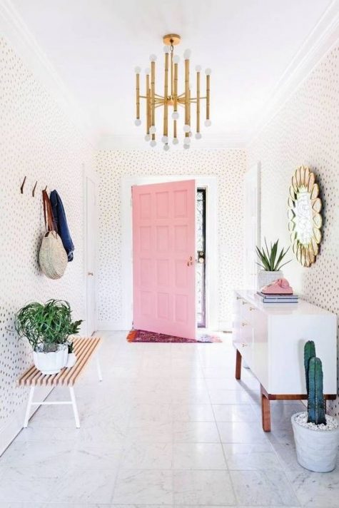 a modern playful and whimsical entryway with polka dot walls, a white sideboard, a bench, clothes racks and a mirror