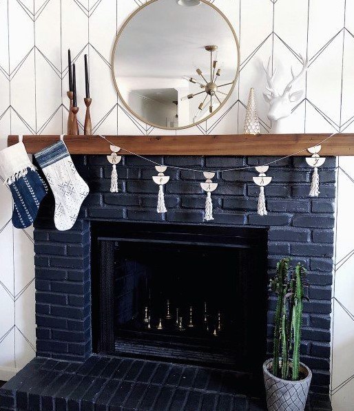 a navy brick fireplace with a wooden mantel and some metallic chess inside is a very fresh take on a traditional piece