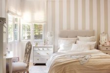 a neutral serene bedroom with a tan and white accent wall, neutral textiles and refined furniture is very welcoming