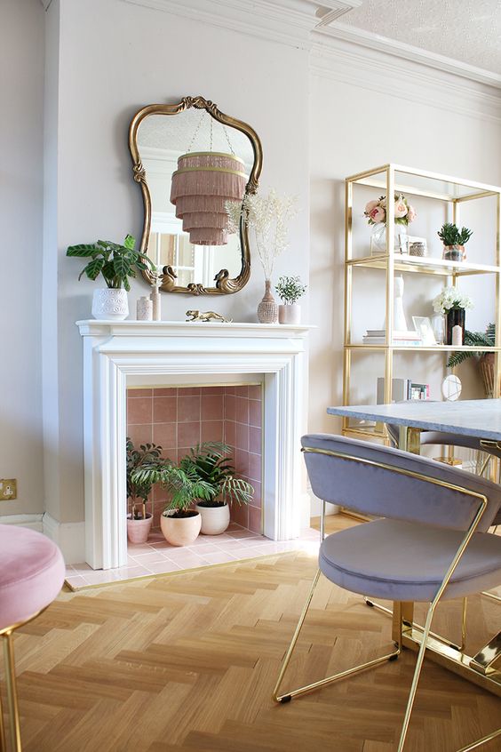 a non-working fireplace clad with pink tiles, with potted plants inside is a cool addition to a bright space