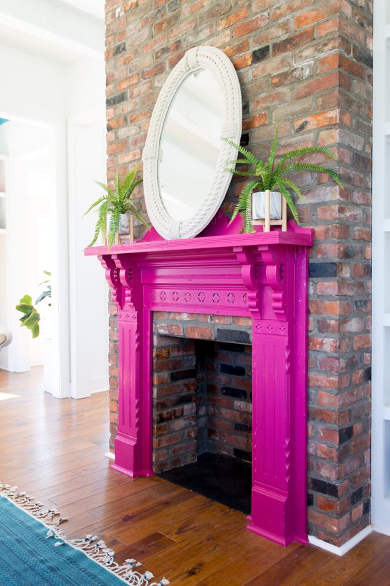 a non-working fireplace with a fuchsia mantel, potted plants and a mirror in a rope frame is a cool idea