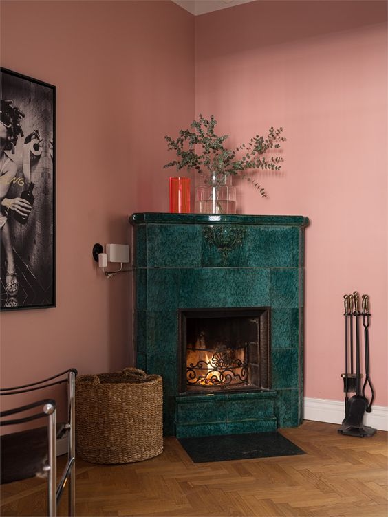 a pink living room with a green tile fireplace, a basket and a stand with tools is an elegant and chic space