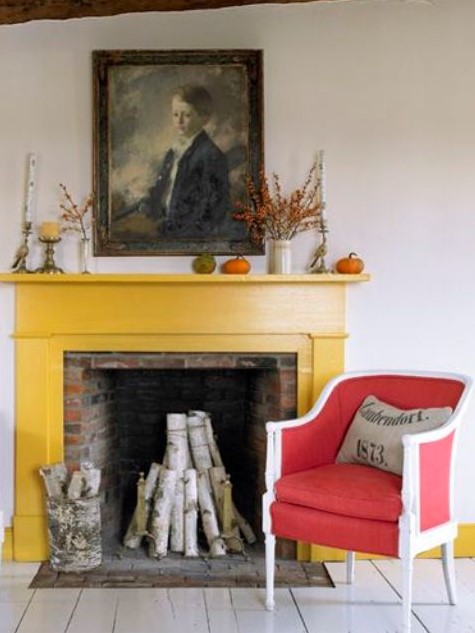 a red brick fireplace clad with a bold yellow mantel and a bright red and white vintage chair, some vases and candleholders