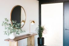 a stylish modern entryway with a round mirror, a basket, a plant on a stand and a boho rug