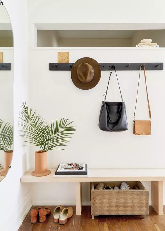 a stylish modern entryway with a sleek bench, a clothes rack, a storage box and a mirror on the wall