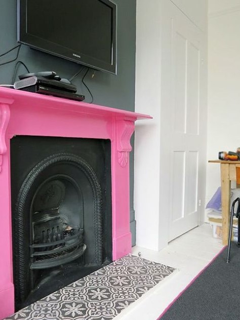 a vintage black metal fireplace and a hot pink mantel over it is a bold and chic touch of color with a playful feel
